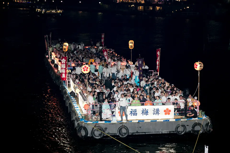 夜の天神祭船渡御で提灯の灯りに包まれた福梅講の奉仕船